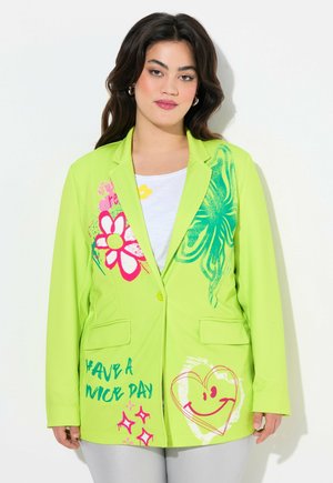 Heller grüner Blazer mit floralen und Smiley-Grafiken in Pink und Blau. Verfügt über zwei Vordertaschen und einen einknöpfbaren Verschluss.