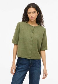 Krótki rękaw, ciemnozielony kardigan z okrągłym dekoltem, zapinany na guziki z przodu, o luźnym fasonie; dzianinowa faktura z prążkowanymi brzegami.