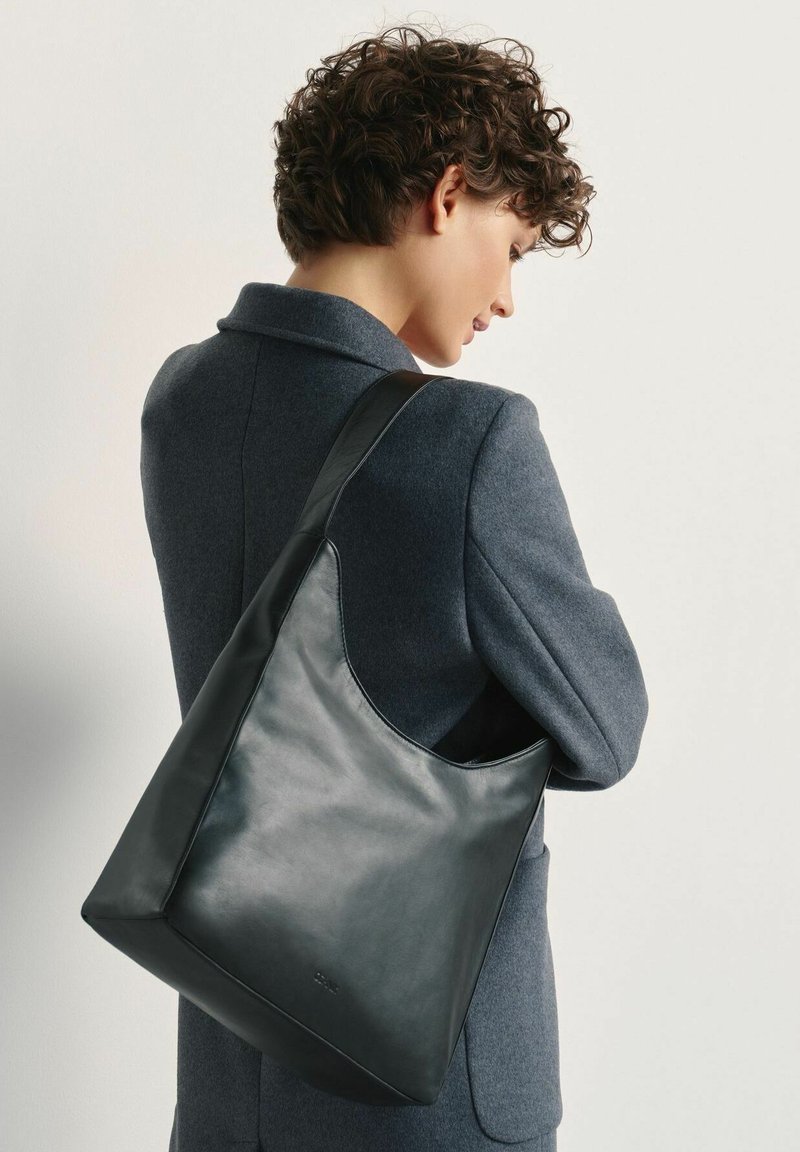 Czarna skórzana torba na ramię o gładkiej fakturze, kanciastym kształcie i szerokim pasku, zaprezentowana na jednolitym tle.