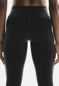 Schwarze, hoch geschnittene Leggings aus dehnbarem Material, mit glatten Nähten und einem anliegenden Design ohne sichtbare Muster oder Hardware.