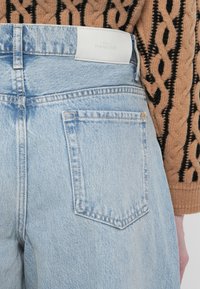Lyseblå denim høyt liv jeans med fem-lomme design og subtil falming. Har et hvitt skinnmerke ved midjen.