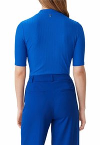 Modrý žebrovaný top s krátkými rukávy, detaily na knoflíky na zadní straně, měkká tkanina a přiléhavý střih, spojený s odpovídajícími modrými kalhotami na míru.