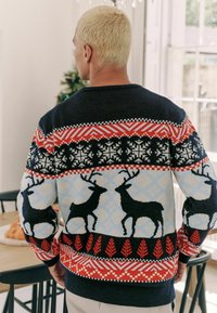Pulover tricotat cu un corp bleumarin, prezentând modele geometrice multicolore, motive cu reni și accente roșii sub formă de frunze la tiv și manșete.