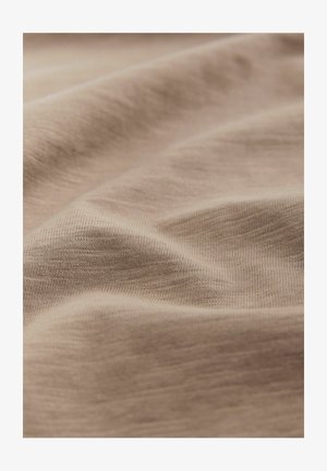 Light beige fabric with a smooth texture, featuring soft folds and subtle variations in color. Cotton blend with fine ribbed detailing.