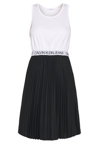 Svart plisserad klänning med en vit linneöverdel och ett brett elastiskt midjeband med texten "CALVIN KLEIN JEANS." Slät textur.