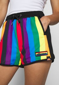 Shorts rayés arc-en-ciel avec une taille noire. Fabriqués dans un tissu lisse et léger. Présentent une étiquette logo à l'ourlet. Cordon de serrage réglable.