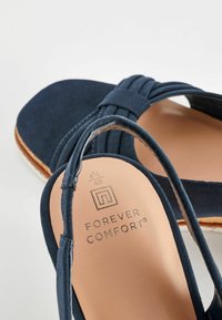 Sandales en daim bleu marine avec brides tressées, orteils ouverts, brides à la cheville et semelles intérieures couleur beige portant la mention "Forever Comfort" taille 6½/40.
