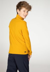 Pullover in pile giallo con colletto alto e maniche lunghe. Presenta un orlo cucito e una piccola etichetta sul lato sinistro inferiore.