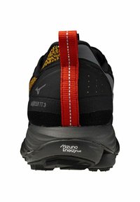 Chaussure de course Mizuno noire avec un dessus texturé, un onglet sur le talon orange et une semelle intermédiaire grise. Présente un logo et des détails de motif sur le talon.