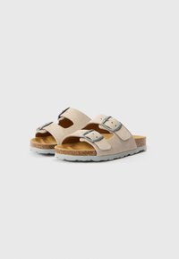 Bézs színű velúr szandál két állítható pánttal, ezüst csatokkal, parafa talpbéléssel és gumi talppal, légáteresztő kivágásokkal.