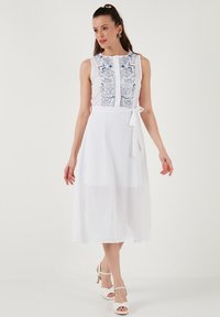 Weißes Ärmeloses Kleid mit detaillierter blauer Stickerei auf dem Oberteil, A-Linie Form, Stoffgürtel zum Binden in der Taille und fließender Maxi-Länge.