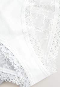 Witte katoenen onderkleding met ingewikkelde kantafwerking en bloemenpatronen langs de randen, en een gladde, zachte textuur.