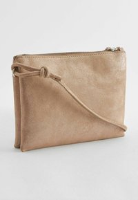 Svetloružový, štruktúrovaný kožený clutch s uzáverom na zips. Obsahuje uzlový popruh a jemný kovový lesk na povrchu. Kompaktný obdĺžnikový tvar.
