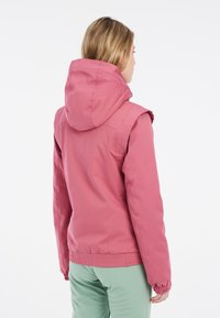 Rosa, kapuzenshirtjacke mit einer strukturierten, glatten Oberfläche. Verfügt über elastische Bündchen und einen gerafften Saum. Wird mit hellgrünen Hosen getragen.