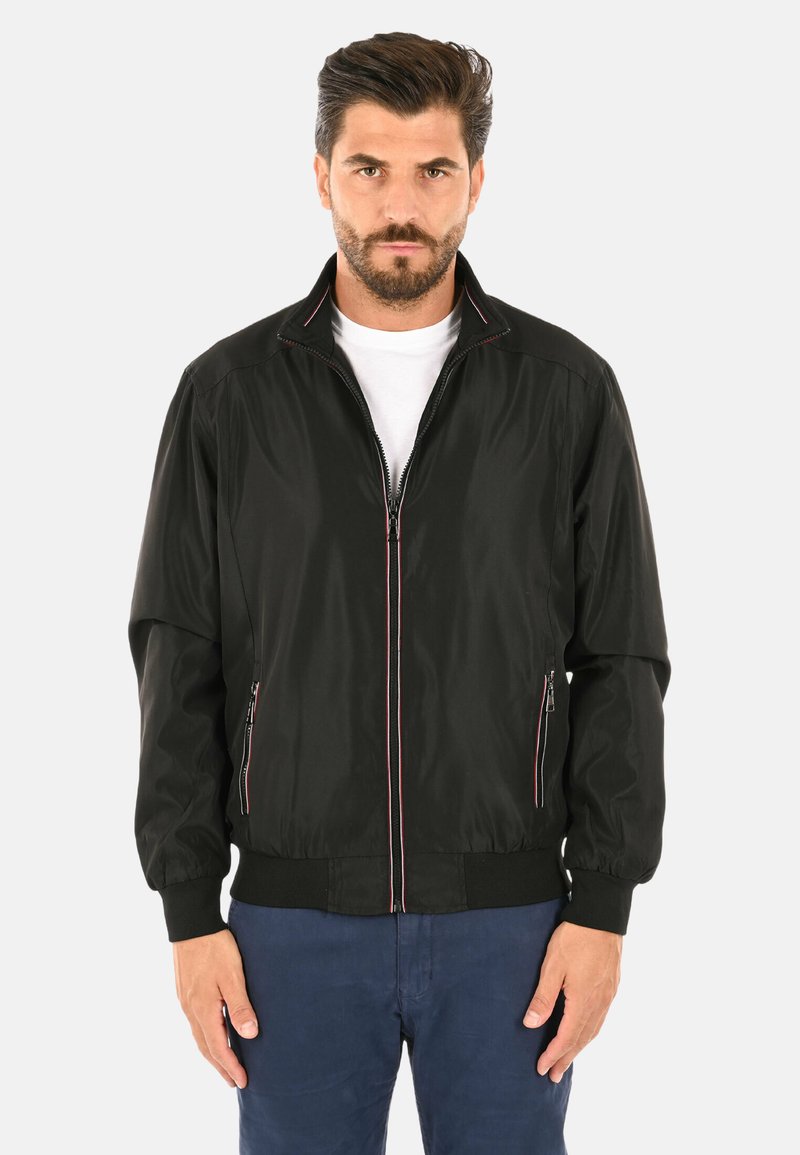 Giacca bomber nera con zip frontale, cuciture rosa a contrasto e tasche laterali. Realizzata in tessuto leggero, presenta polsini e vita elasticizzati.