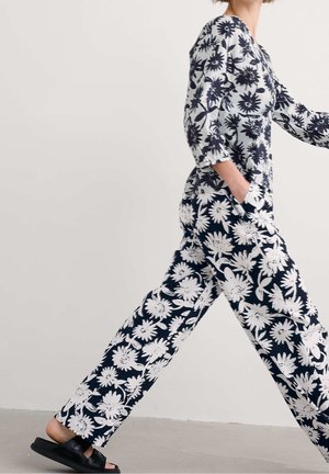 Ensemble deux pièces en tissu bleu marine avec des motifs floraux blancs. Le haut a des manches longues ; le pantalon est ample avec des poches.