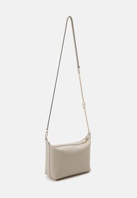 Beige leather shoulder bag with a curved design, gold hardware accents, zipper closure, and a detachable chain and leather strap.
