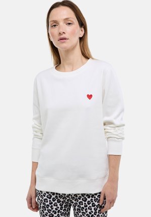 Sweat-shirt blanc en tissu doux avec un col rond et des manches longues, orné d'un petit cœur rouge brodé sur le côté gauche de la poitrine.