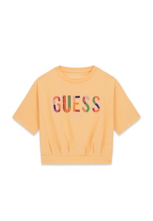 Kurzes, pfirsichfarbenes, bauchfreies T-Shirt mit mehrfarbigem "GUESS"-Schriftzug und der Aufschrift "EST. 1981" auf der Vorderseite.