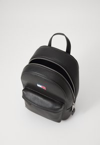 Schwarzer Leder-Rucksack mit strukturierter Oberfläche, zwei Reißverschlussfächern, einer Vortasche und einem kleinen Markenlogo auf der Vorderseite.