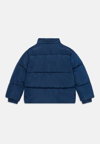 Temno modra puffer jakna z visokim ovratnikom, vodoravno šivanimi paneli in rebrastimi manšetami. Gladka tekstura, izolirana zasnova za toploto.