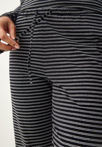 Svartvita randiga stretchbyxor med resår i midjan och dragsko. Har en sidoficka och slät textur.