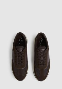 Pruunid tossud, mis on valmistatud segatud nahast ja võrgumaterjalist, kummikudega, ümarate varvastega ja valge kummiseguga. 