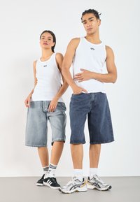 White ribbed tank tops, light blue and dark blue denim shorts, black and white sneakers, and athletic shoes with gray, white, and yellow accents.
