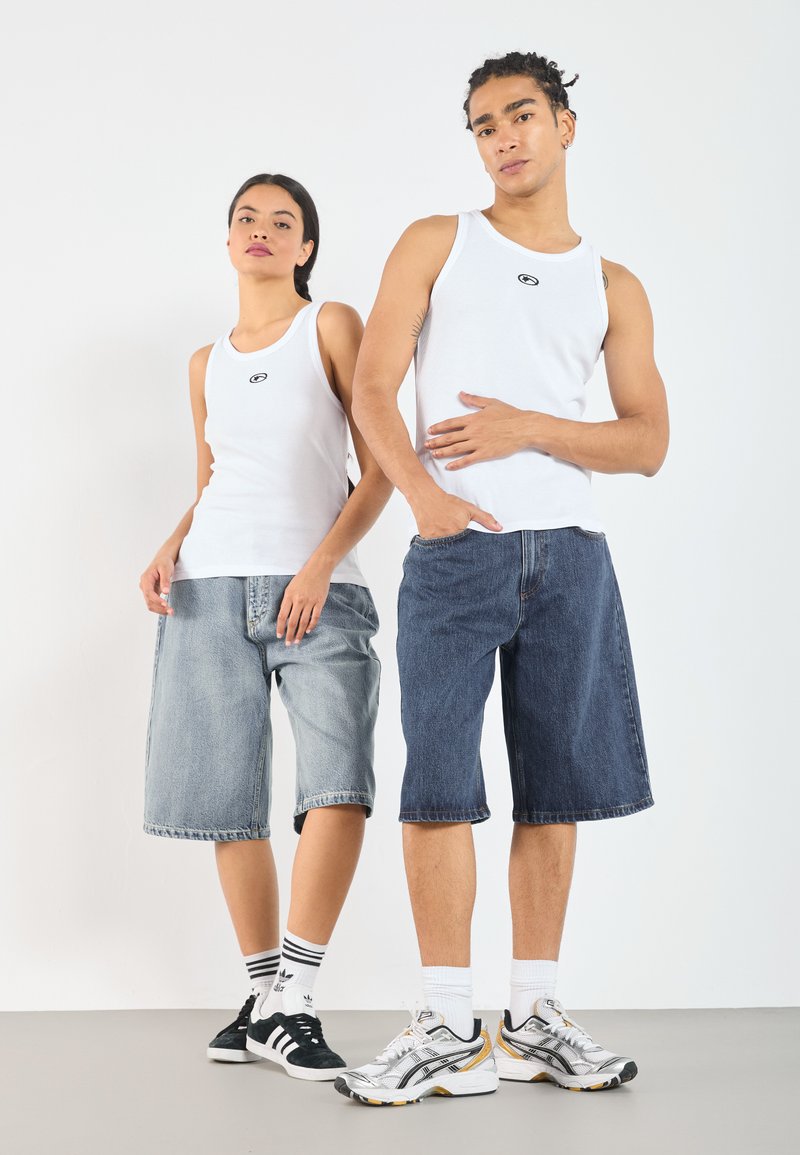 Vita ribbade linnen, ljusblå och mörkblå denimshorts, svarta och vita sneakers, samt träningsskor med grå, vit och gul accent.