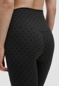 Fekete leggings, texturált pöttyös mintával. Magas derék kialakítás, sima anyag, amely passzos megjelenést biztosít.