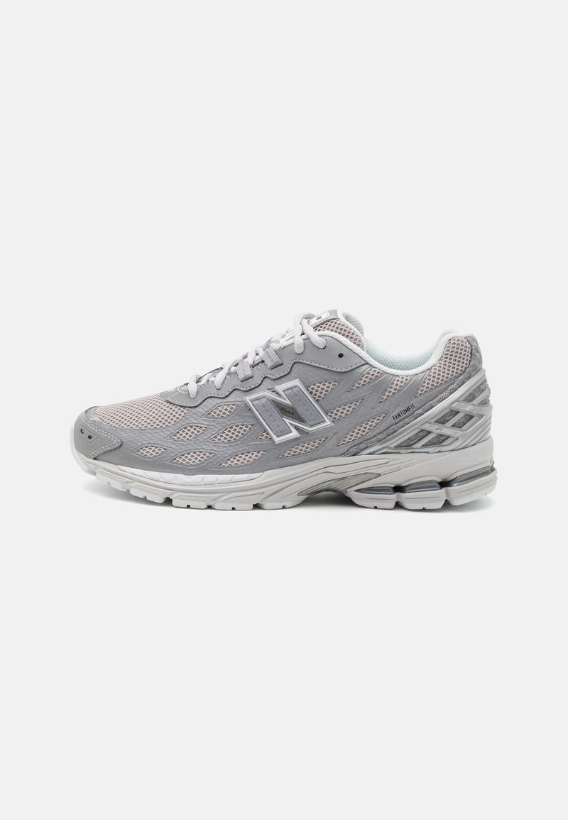 Chaussure de course New Balance grise et blanche avec tige en mesh, lacets à l'avant, semelle rembourrée et marquage sur le côté et le talon.