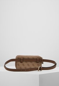 Hnědá kožená kabelka se strapcem, která má strukturované tělo v odstínu tan s monogramovým vzorem, zipovým uzávěrem a nastavitelným popruhem.