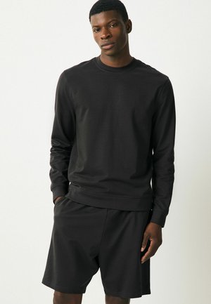 Sort afslappet sweatshirt og shorts sæt, lavet af glat stof. Har en rund halsudskæring og lange ærmer med ribbede manchetter og talje.