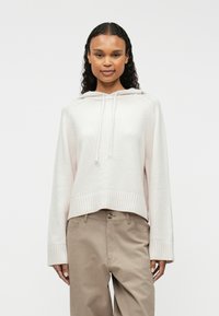 Gaiši rozā apgriezta kapuce, izgatavota no mīksta auduma, ar aukliņu kapuci, ribotām aprocēm un vienkāršu dizainu, apvienota ar beidzamā krāsā biksēm.