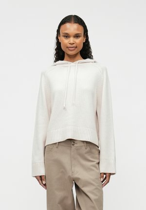 Hellrosa Cropped Hoodie aus weichem Material, mit Kapuze und Kordelzug, gerippten Bündchen und schlichtem Design, kombiniert mit beigen Hosen.