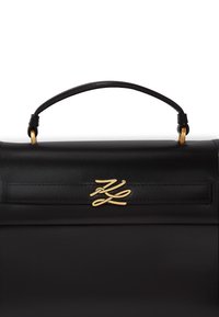 Borsa a tracolla in pelle nera con un design strutturato, manico superiore e hardware dorato. Presenta un logo prominente sul fronte.