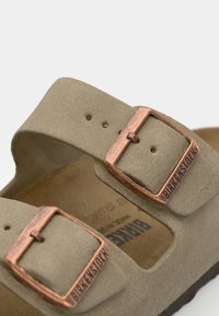 Sandale en daim beige avec deux larges sangles, dotée de boucles couleur bronze. Vue de dessus, mettant en valeur son semelle ergonomique et sa texture douce.