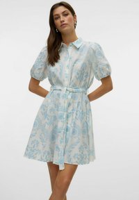 Abito camicia realizzato in tessuto leggero con un motivo floreale blu. Maniche a sbuffo corte, chiusura frontale con bottoni e cintura removibile in vita.