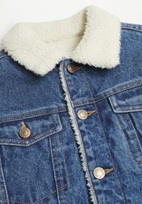 Džínová bunda s měkkým, krémově zbarveným falešným kožíškovým límcem, měděnými knoflíky a dvěma náprsními kapsami s viditelnými detaily šití.