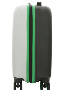 Valigia rigida con colori nero, bianco e verde. Presenta una zip centrale e quattro ruote per la mobilità. Texture liscia.