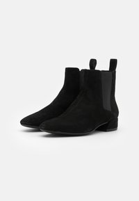 Botas de tobillo de ante negro con paneles laterales elásticos, puntera afilada y tacón bajo en bloque; superficie texturizada con un acabado suave.