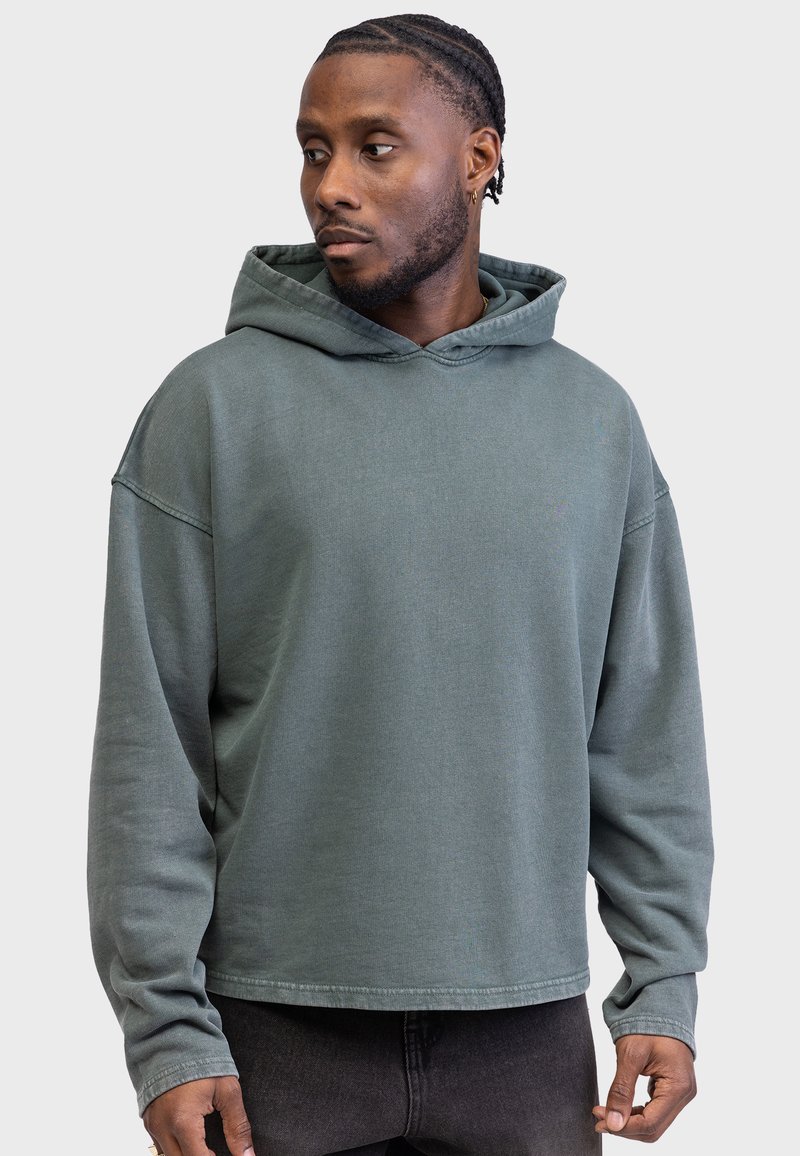 Oversized hooded sweatshirt in gedempt groen, met een ontspannen pasvorm en lange mouwen. Zachte textuur met een eenvoudig, niet versierde ontwerp.