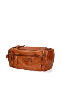 Bruine leren toilettas met een ritssluiting hoofdcompartiment, gestructureerde afwerking en zijvak. Bevat een merklabel aan de voorkant.