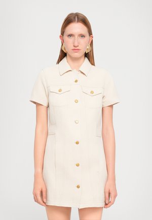 Short-sleeve, cream-colored denim dress with a collared neck, chest pockets, gold buttons, and a fitted silhouette. Smooth texture.