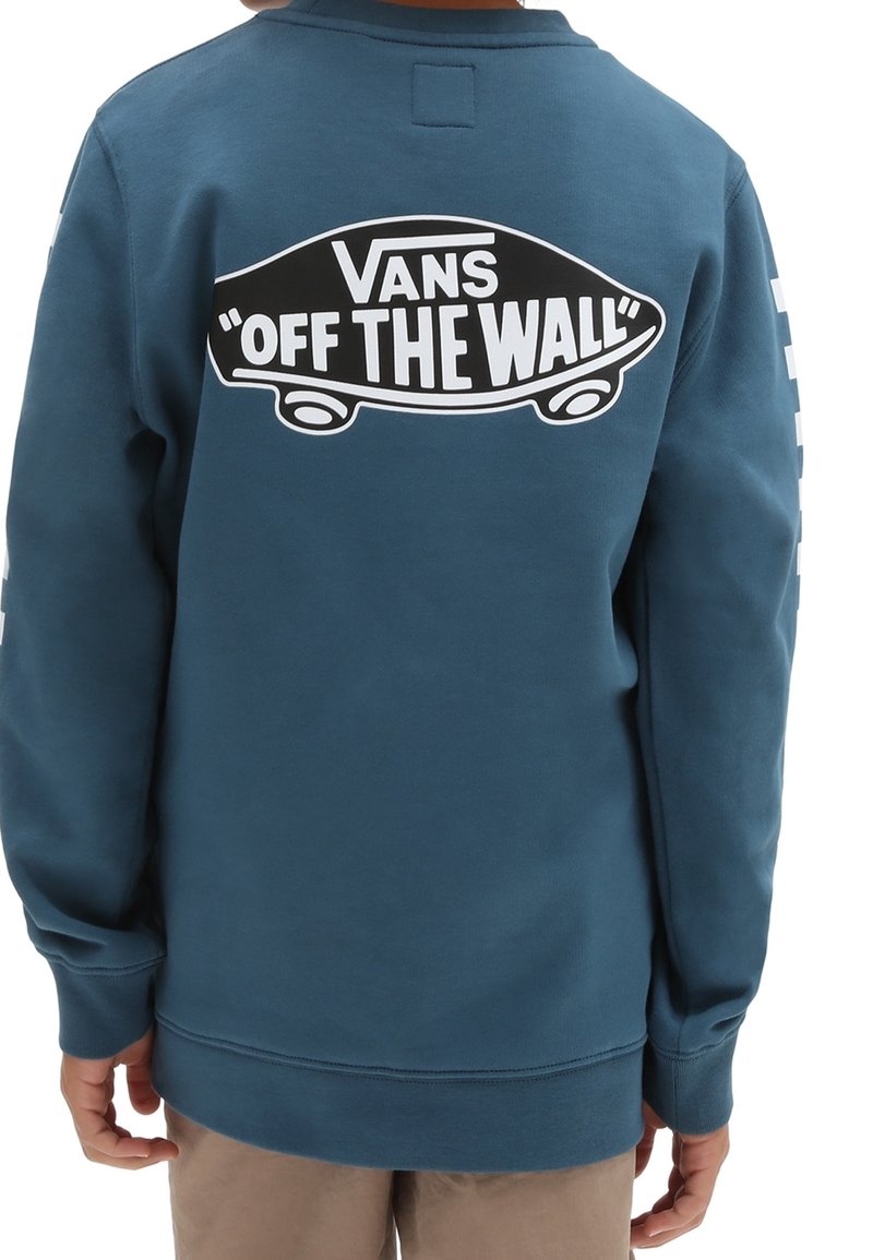 Den blå sweatshirt har en stor svartvita Vans "Off The Wall"-grafik på baksidan, med långa ärmar och ribbade muddar.