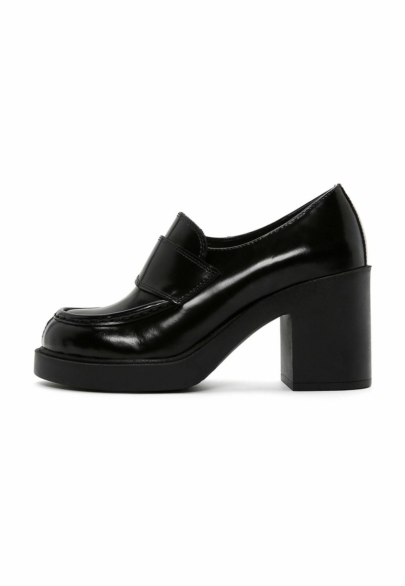 Mocassin pour femme en cuir verni noir avec talon bloc épais et semelle plateforme, doté d'une large bride sur le dessus.