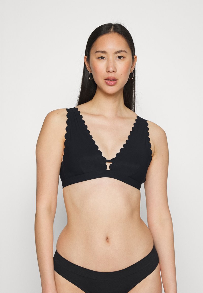 Sutiã preto com bordas em scallop, design de decote em V profundo e detalhe em forma de buraco no centro. Textura suave, estilo minimalista e sem enchimento.