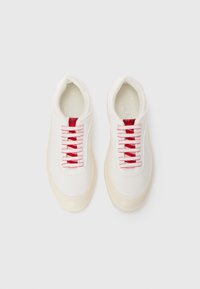 Hvite sneakers med øverdel i glatt lær, røde snørebånd, polstret krage og lys gummisåle. Minimalistisk design uten mønstre.