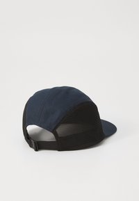Marineblå kasket med en solid front og sort net bag. Har en buet skygge og justerbar rem for tilpasset pasform.