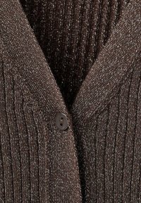 Hnědý pletený kardigan s ribovanou strukturou, s výstřihem do V a jedním hnědým knoflíkovým zapínáním. Materiál obsahuje jemné metalické vlákna.